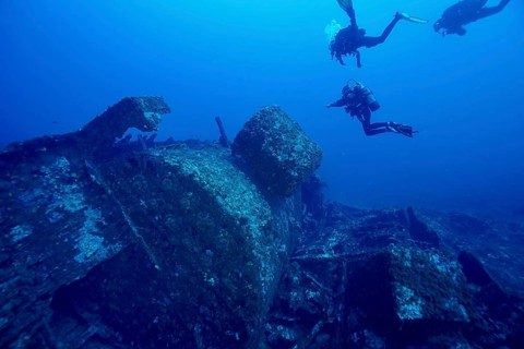 Divers explore a large shipwreck underwater in the deep sea, dive site Wreck Michel C, Hyères,
