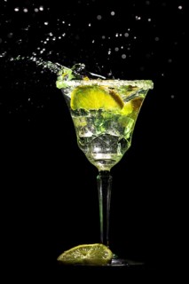 A sparkling cocktail glass with lemon slices and ice cube cubes against a black background