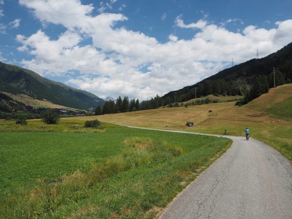 Open landscape with a bike path surrounded by green fields and blue sky with clouds, Rottenweg,