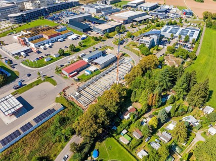 Aerial view of a large construction site with crane and industrial park in the background, Parkhaus