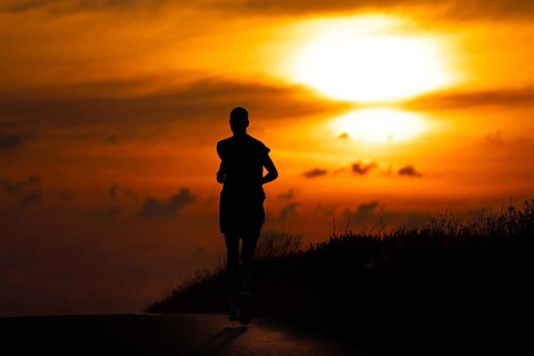 A female jogger runs along a Feldberg near Frankfurt am Main in the morning just after sunrise,