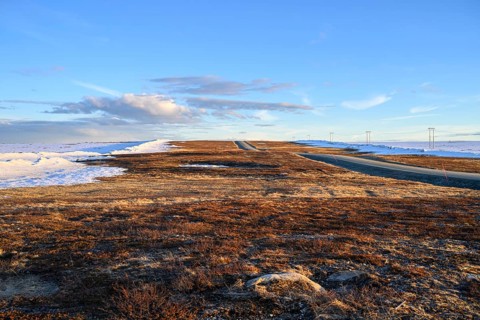 Storsjö Kapell, Jämtlands län, Sweden, A flat, open road on snow-covered terrain with low sun on