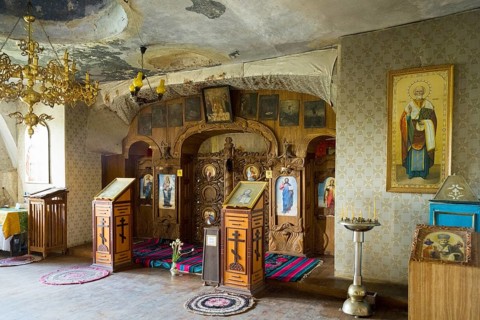 Richly decorated Orthodox interior with icons and candles under a chandelier, cave church, rock