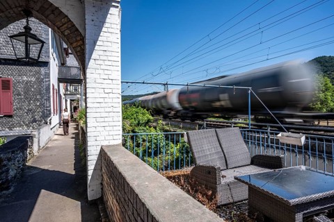 Freight train passing through town in Bacharach, right by the residential buildings, front gardens