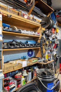 Variety of objects, items including oil and cleaning products arranged on shelves and hand drills