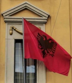 Albanian flag with black eagle attached to a yellow building, Albania