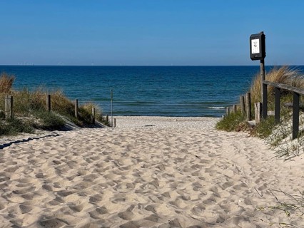 Sand trail leads to a quiet beach with a blue sea and a clear sky, Graal-Müritz,