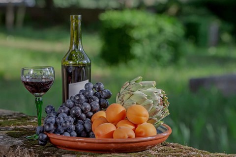 A plate of fruit and vegetables and a bottle of wine outdoors, Provence, France