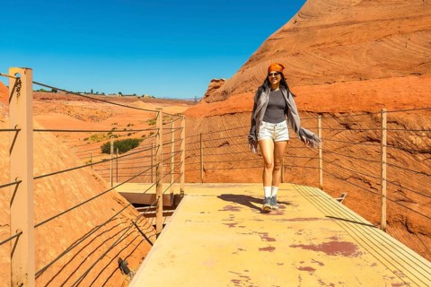 Woman in casual attire walking on a viewing platform through the impressive red sandstone rock