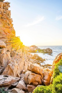 A little trail passing the rocks at the coastline with blue water at Costa Paradiso on a sunny day