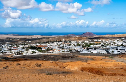 View of town, white houses of Teguise with church tower in dry volcanic landscape, Lanzarote,
