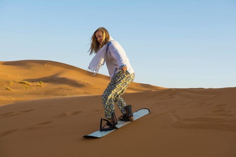 Young woman with snowboard in the sand dunes, near Merzouga, Meknès-Tafilalet region, Erg Chebbi,