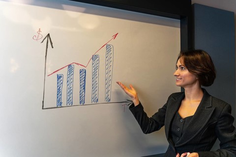 Smiling businesswoman gesturing toward growth chart during corporate presentation