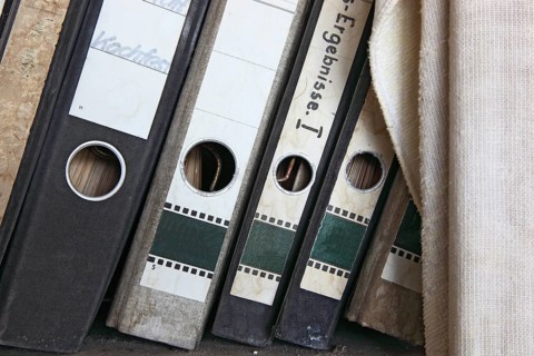 Office scene around 1982, lost place, abandoned location, classic file folders on a wooden shelf,