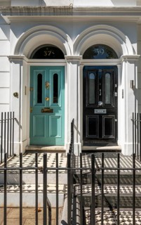 House entrances with turquoise and black entrance doors, mosaic tiles and wrought iron fence in