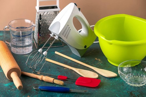 Kitchen utensils such as mixer, bowl, and rolling pin on a table
