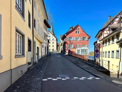 Narrow, steep cobblestone road with colorful, historic buildings and blue sky, Diessenhofen, Canton
