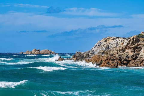 Coastline with emerald green and blue water on a sunny day at Rena Majori beach, Sardinia, Italy