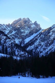 Dramatic snowy mountains with deep forest in the foreground under clear, bright skies, Pragser