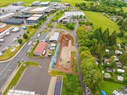 Industrial buildings and a construction site with surrounding roads and forests from the air in