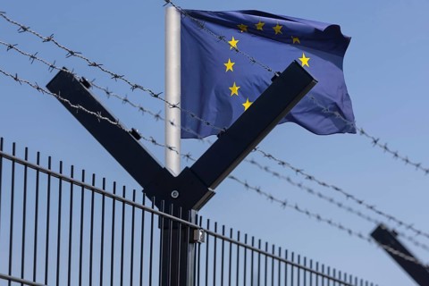 (photo montage) Symbolic image: EU flag behind security fence with barbed wire
