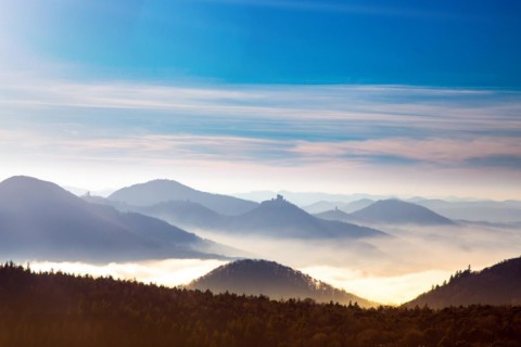 Autumnal panorama of the Palatinate Forest with mountain peaks and valleys in the mist. Trifels