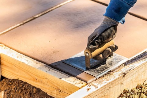 Construction Worker Using Hand Groover On Wet Cement Forming Coping Around New Pool