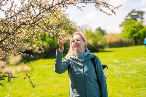 Woman standing in front of a blooming tree and smiling in a spring meadow, Naturführung Heckengäu,