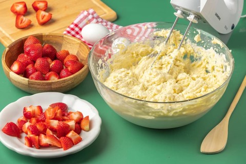The dough is mixed, sliced strawberries ready to be added, everything on a green table