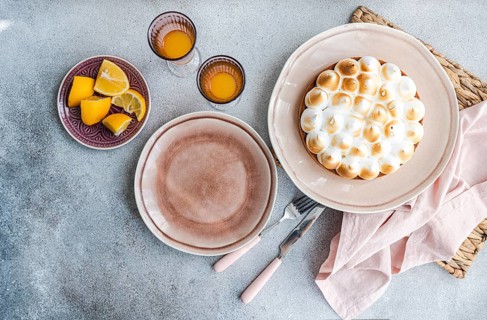 A rustic table setting features a homemade lemon cake with citrus slices on a plate. The