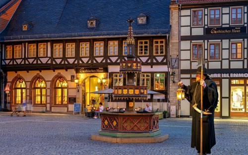 Night watchman in front of Wohntäterbrunnen illuminates Wernigerode Harz Germany