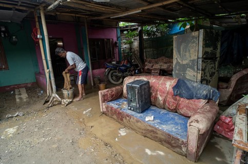 Resident cleaning inside his mud-filled and flood-damaged home after floodwaters receded on July