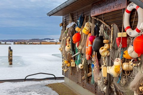 Old fenders, fishing nets and lifebuoys on boathouse in the Gager harbour in winter, Mönchgut