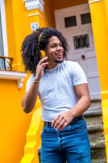 Vertical photo of an african young man listening to music with headphones in the street next to