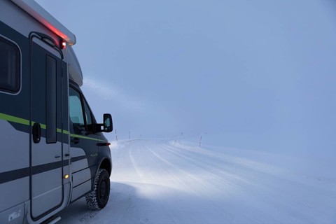 Motorhome blowing in snow on snowy road, Lapland, Norway