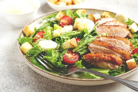 Caesar salad, with duck breast, on a light plate, on a light background, homemade, no people