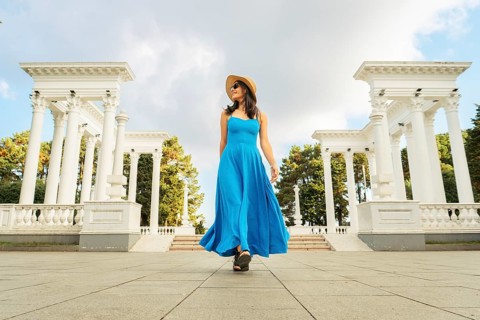 Woman in blue dress walking toward Batumi colonnades, neoclassical landmark with white columns on