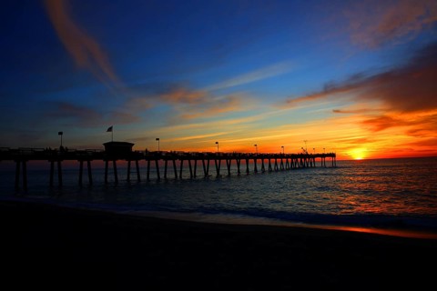 A pier against a colorful sky at sunset, calm sea and carefree atmosphere, Naples pier on the beach