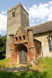 Red brick Tudor porch and flint tower of village parish church of Saint Andrew, Winston, Suffolk,