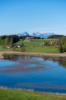Panorama with mountains, a lake and green meadows under clear sky, Biberschwöller See, Steingaden,