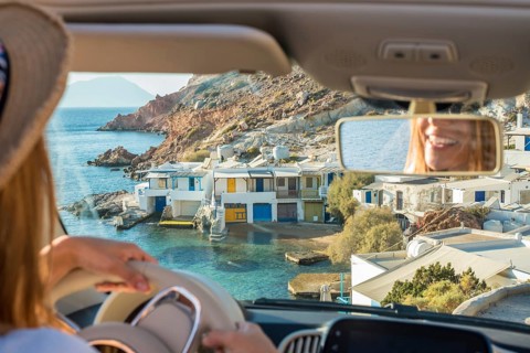 A driver enjoys a scenic view of the charming coastal village of Fourkovouni on Milos Island,