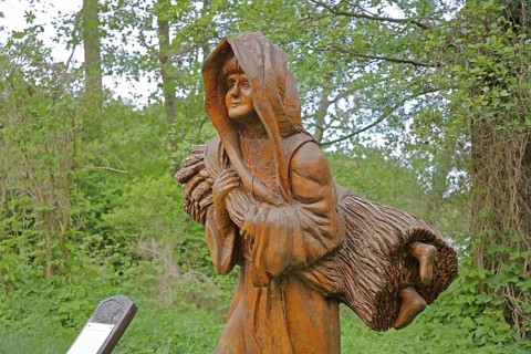 Wooden sculpture of legend on the straw bridge, monk secretly smuggles child in sheaf into the