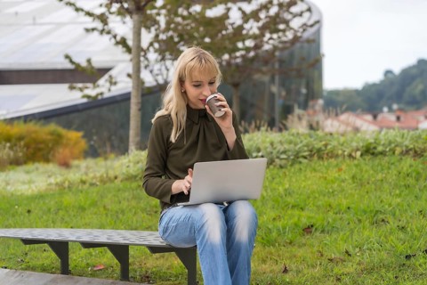 Caucasian blonde girl entrepreneur in business park conducting a video conference with a take away
