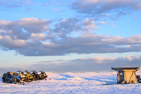 Ljungdalen, Jämtlands län, Sweden, snowy landscape with snowmobiles and a small hut under a blue