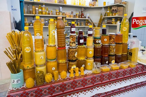 Market stand with a wide range of honey products in jars and bottles decorated with traditional
