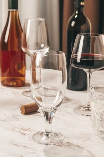 A table displays various wine glasses alongside a bottle of wine. Some glasses are empty while