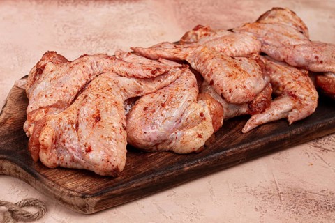 Chicken wings, marinated and laid out on a wooden platter, ready for cooking, grilling or baking,