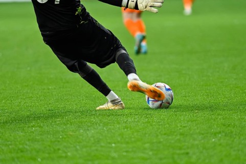 Football goalkeeper kicks ball. Player's legs and the ball during soccer match in Lubin, Poland
