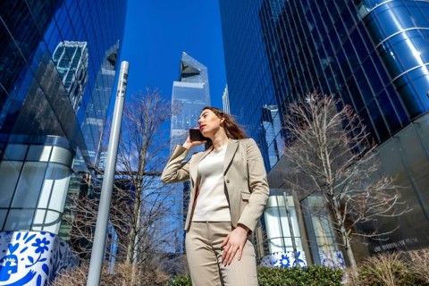 Young businesswoman communicating on a smartphone while walking among modern skyscrapers,