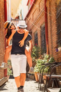 Beautiful young tourist couple Happy caucasian couple having fun piggyback visiting walk narrow